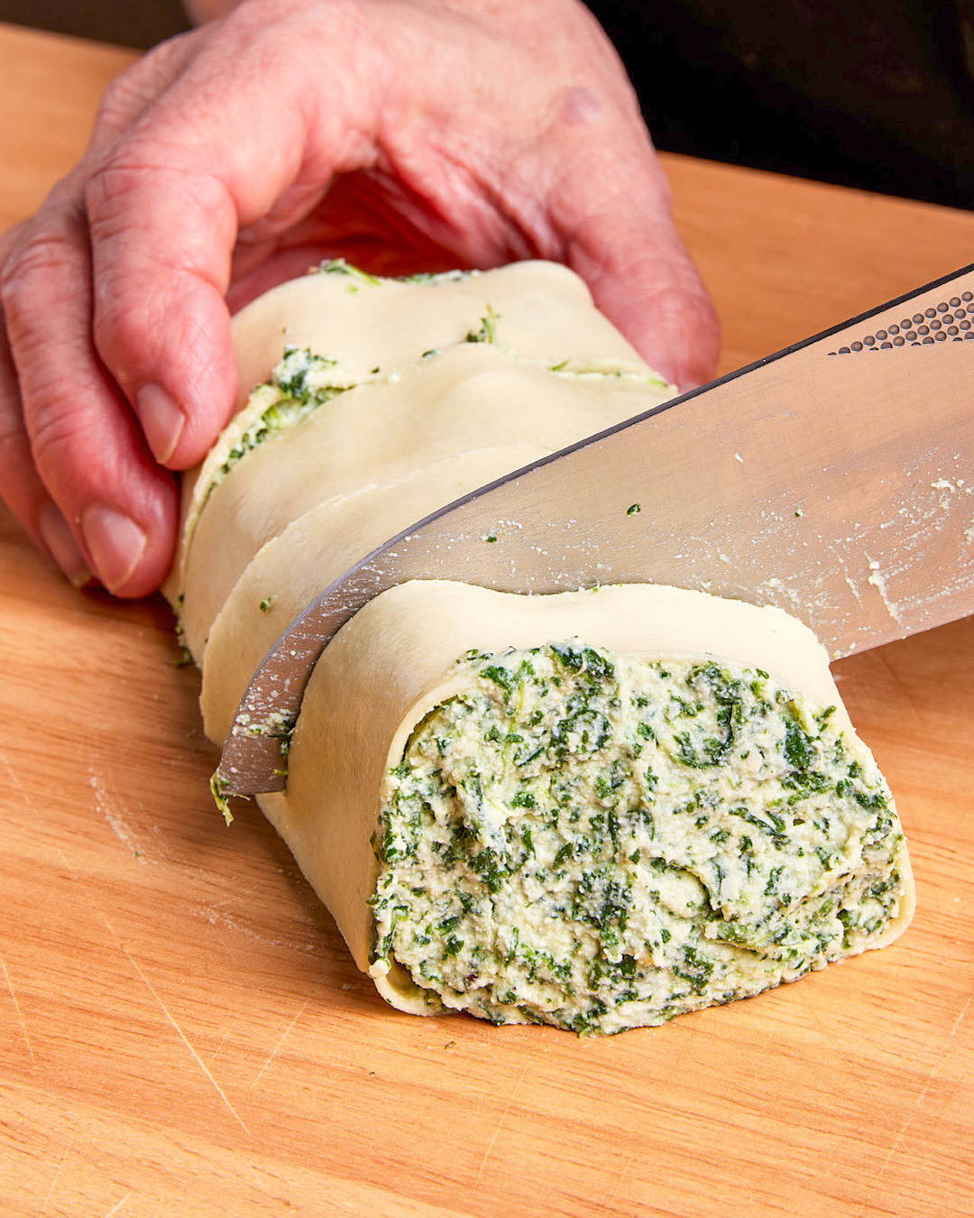 6. Using a chef’s knife, carefully cut each chilled pasta roll crosswise into 4 slices, each about 1 inch thick. Try not to the rolls as you cut them.