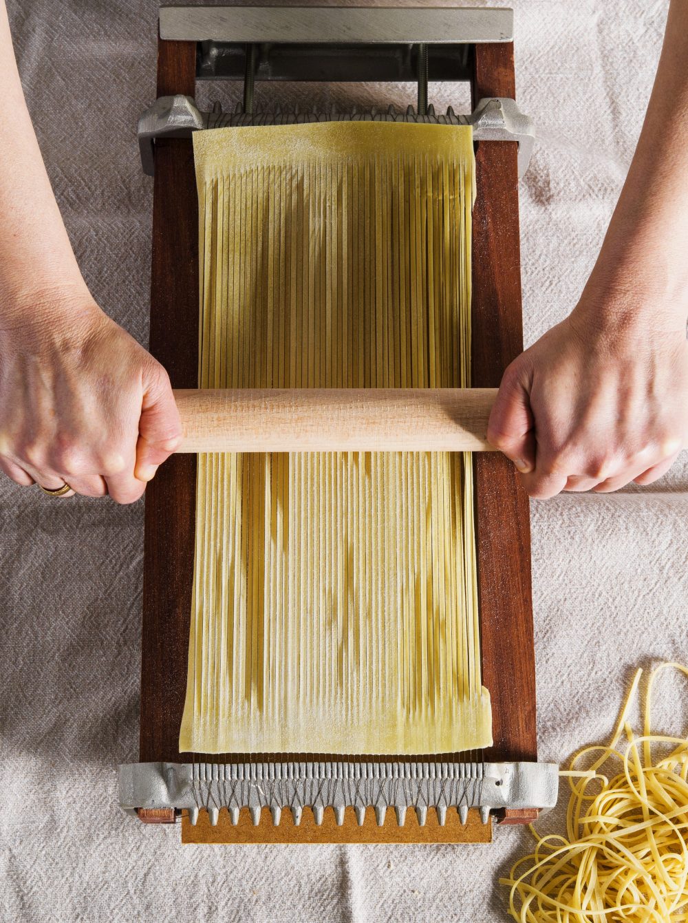 A chitarra tool cuts fresh pasta sheets into thin strands.