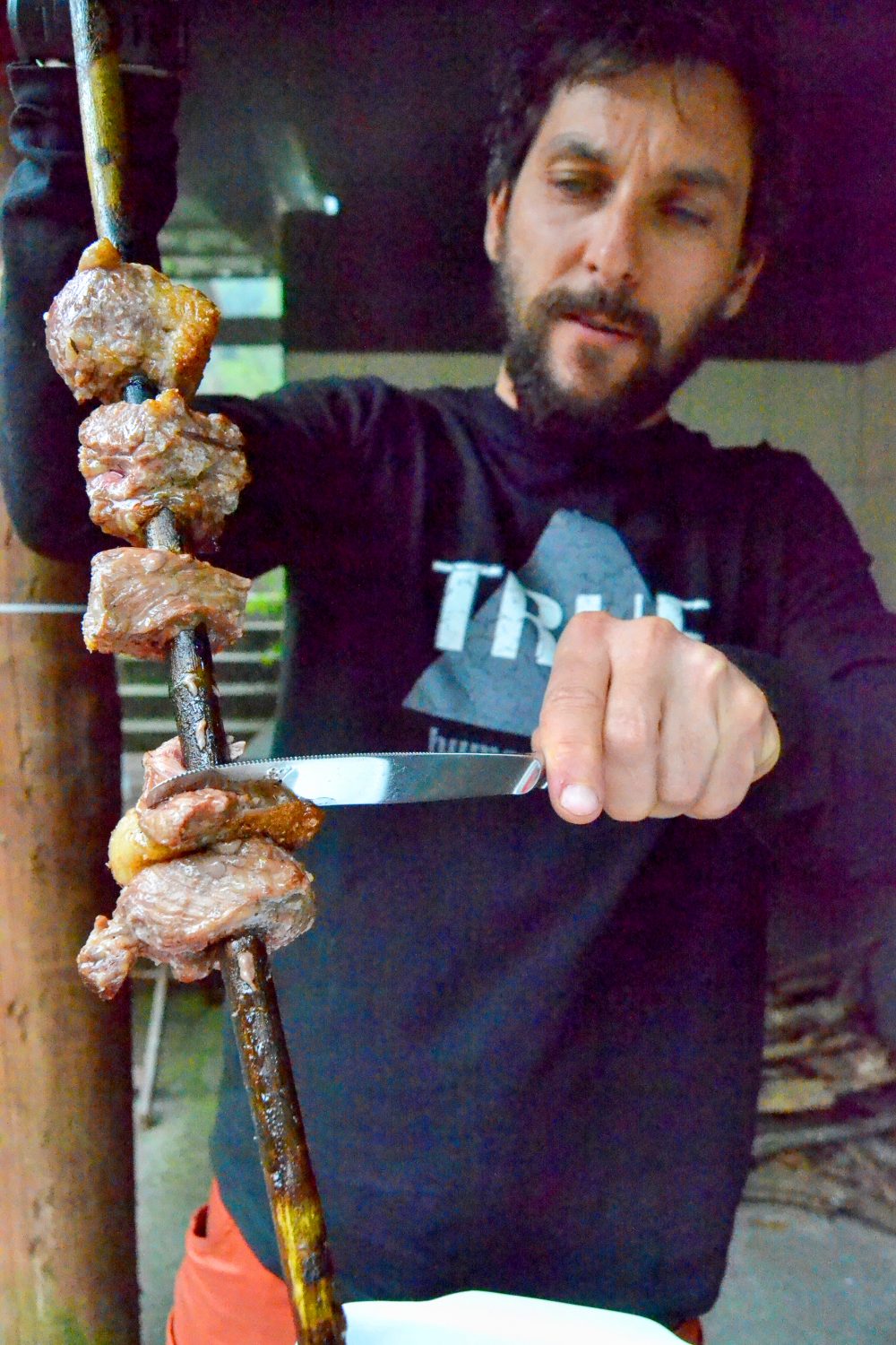 ​Roberto Góis pulls beef from a spear of laurel.